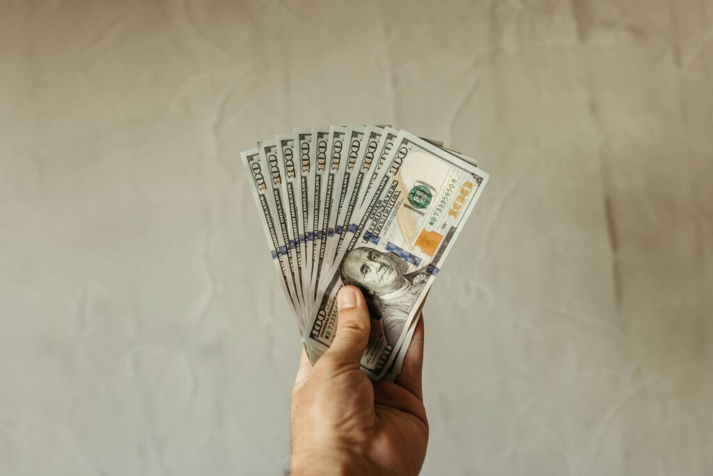 A hand with 100 dollar bills in the shape of a fan