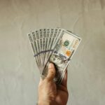 A hand with 100 dollar bills in the shape of a fan